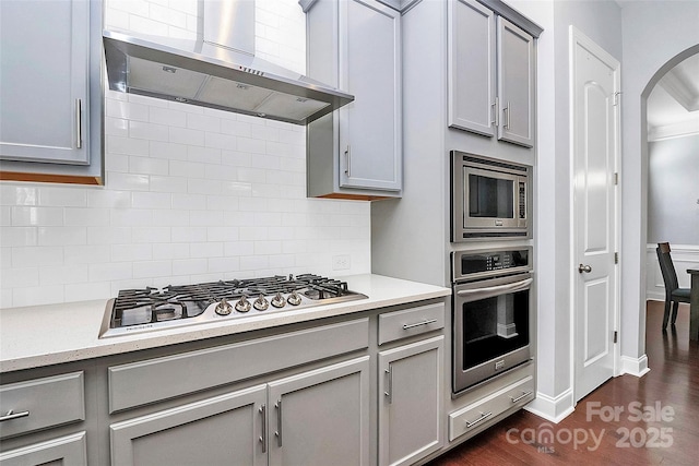 kitchen featuring gray cabinetry, stainless steel appliances, and wall chimney range hood