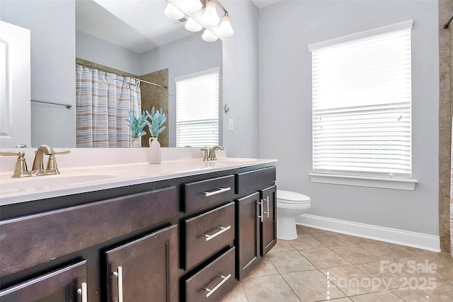 bathroom with vanity, tile patterned floors, toilet, and a healthy amount of sunlight