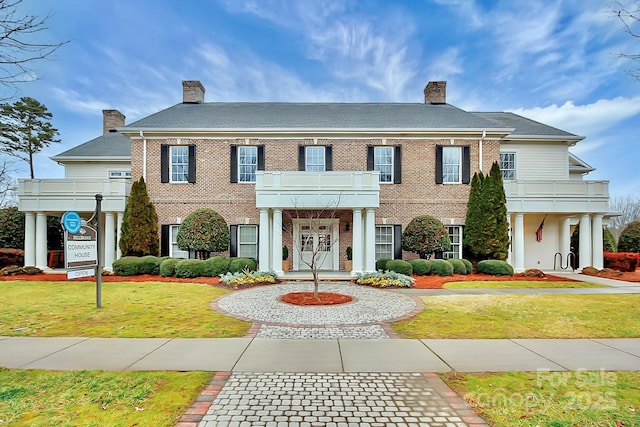 colonial house with a front lawn and a balcony