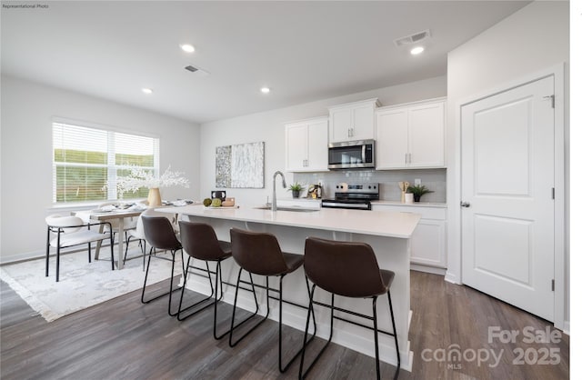 kitchen featuring tasteful backsplash, sink, white cabinets, a kitchen island with sink, and stainless steel appliances