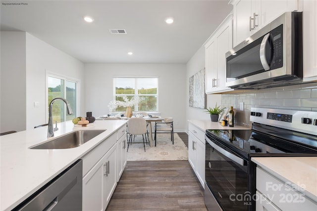 kitchen with appliances with stainless steel finishes, sink, white cabinets, and backsplash