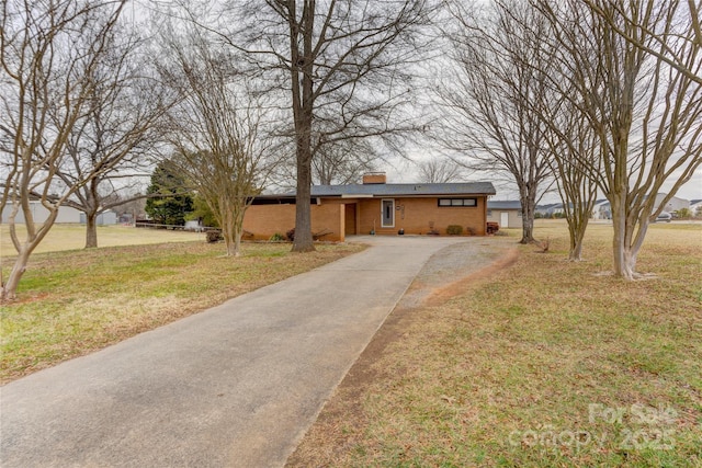 view of front of property with brick siding, a chimney, and a front yard