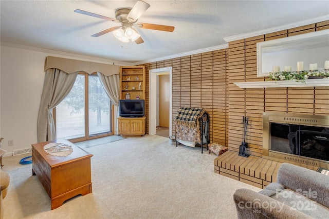 carpeted living room with a textured ceiling, a fireplace, a ceiling fan, and crown molding