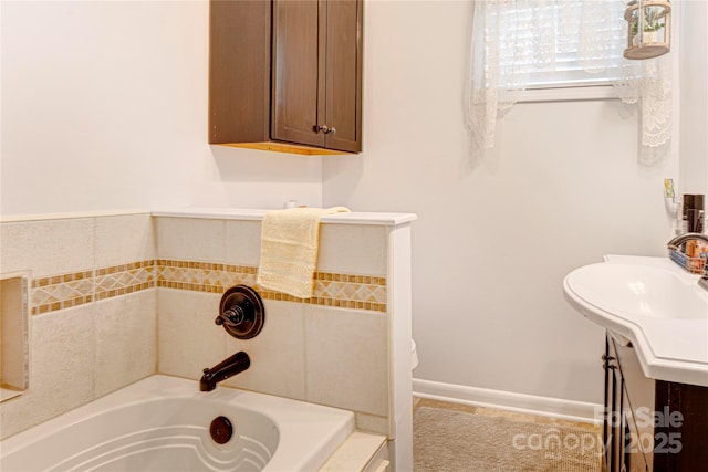 full bath featuring vanity, a washtub, and baseboards