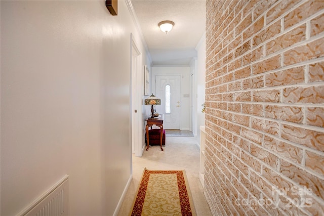 corridor with light carpet, brick wall, visible vents, and baseboards