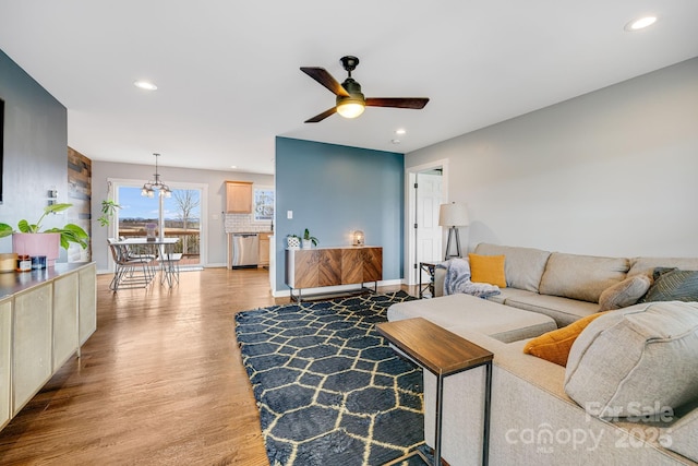 living room featuring light hardwood / wood-style floors and ceiling fan with notable chandelier