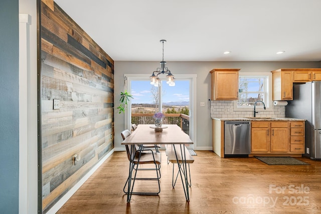 kitchen featuring light wood-type flooring, sink, hanging light fixtures, and stainless steel appliances