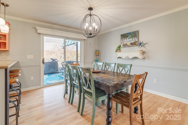 dining area with ornamental molding, a chandelier, and light hardwood / wood-style flooring