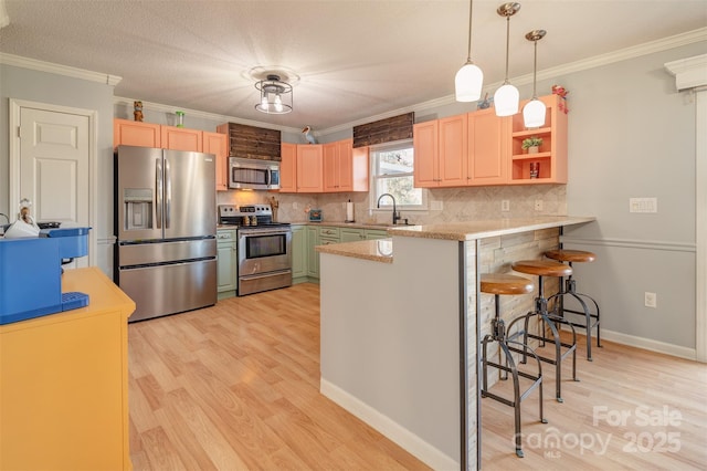 kitchen with a breakfast bar, hanging light fixtures, ornamental molding, kitchen peninsula, and stainless steel appliances