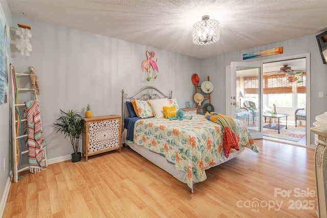 bedroom featuring an inviting chandelier, access to exterior, light hardwood / wood-style floors, and a textured ceiling