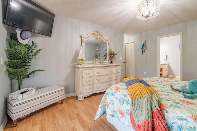 bedroom featuring connected bathroom, an inviting chandelier, a textured ceiling, a closet, and light hardwood / wood-style floors