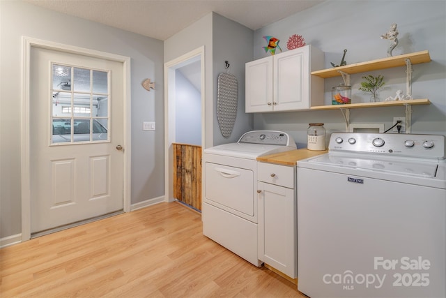 clothes washing area with cabinets, washer and clothes dryer, and light hardwood / wood-style floors