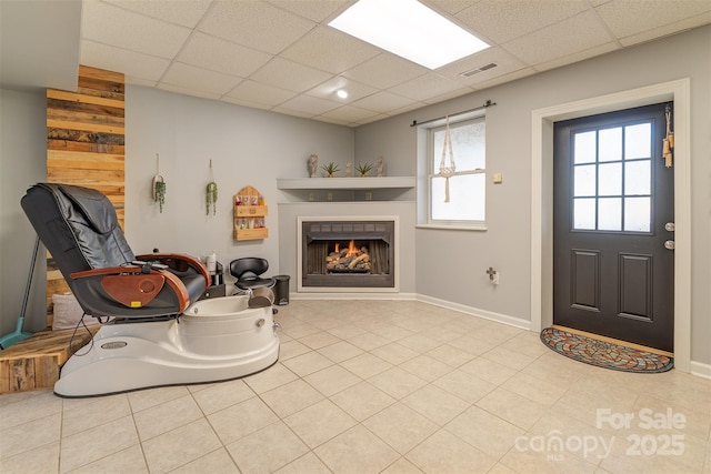 interior space with a paneled ceiling and light tile patterned floors