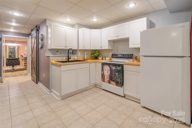 kitchen with white cabinetry, a barn door, sink, and white appliances