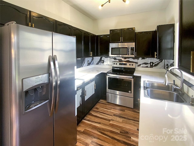 kitchen featuring stainless steel appliances, sink, dark wood-type flooring, and decorative backsplash