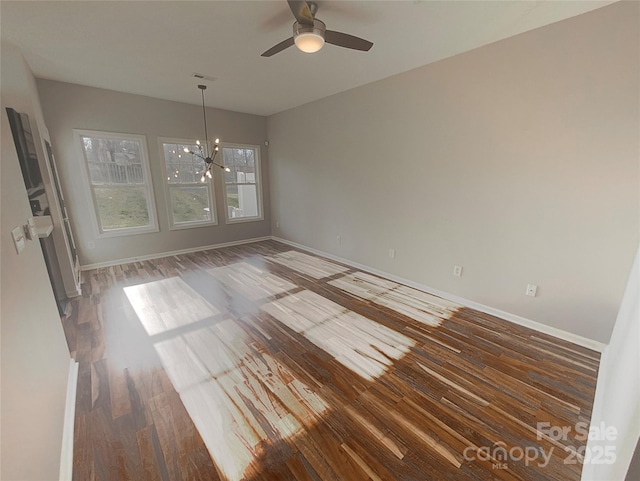 unfurnished dining area featuring ceiling fan with notable chandelier and dark wood-type flooring