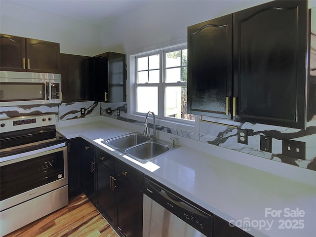 kitchen with stainless steel appliances, sink, and light hardwood / wood-style flooring