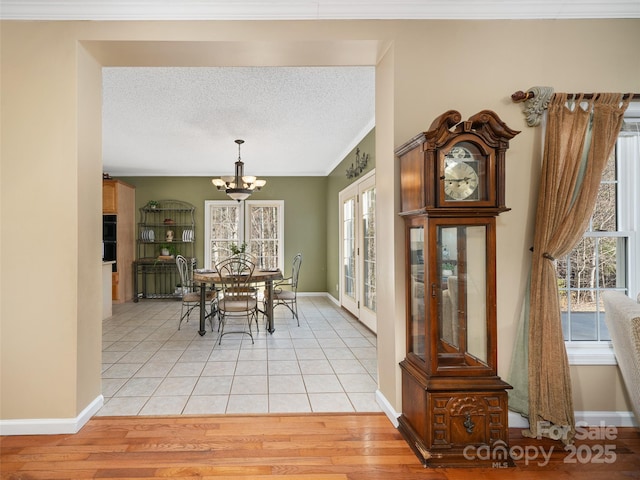 dining area featuring a notable chandelier, crown molding, a textured ceiling, and light wood-type flooring