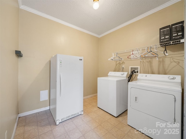 laundry area featuring ornamental molding, washing machine and dryer, and a textured ceiling