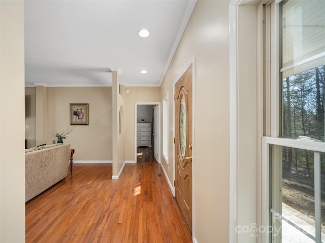 corridor with ornamental molding and light hardwood / wood-style floors