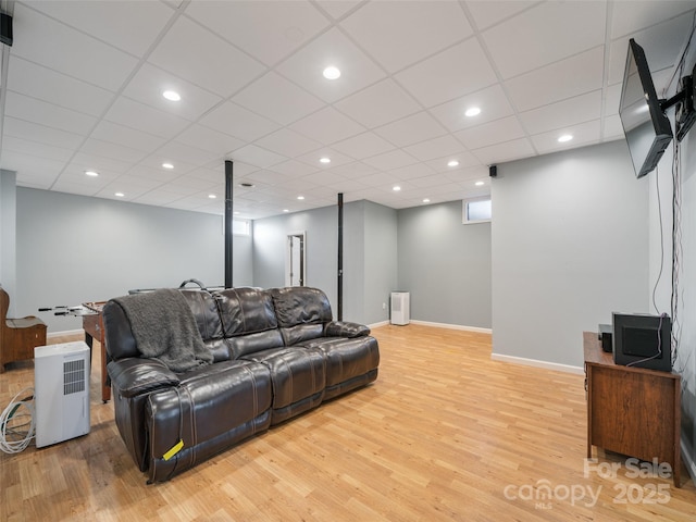 living room featuring a drop ceiling and light hardwood / wood-style flooring