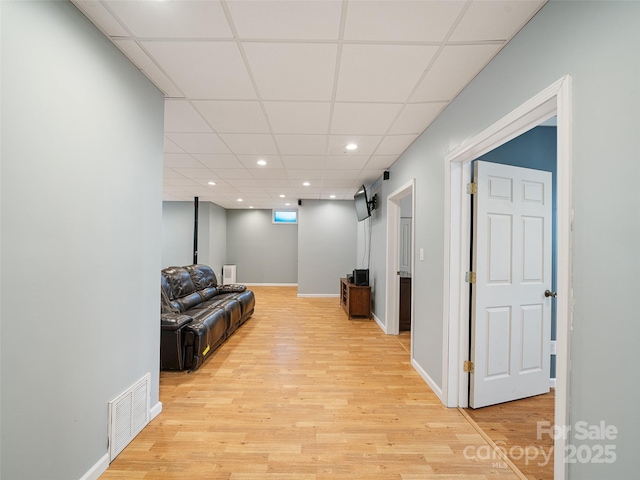 living room with light hardwood / wood-style flooring and a paneled ceiling