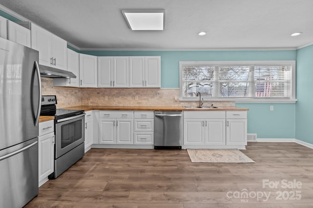 kitchen featuring sink, stainless steel appliances, tasteful backsplash, wood-type flooring, and white cabinets