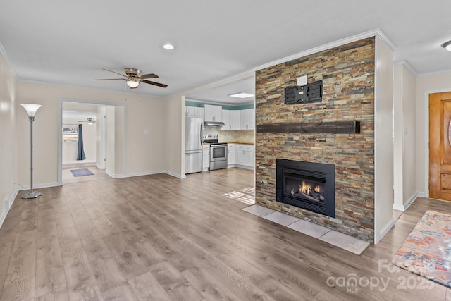 unfurnished living room featuring crown molding, ceiling fan, a stone fireplace, and light hardwood / wood-style flooring