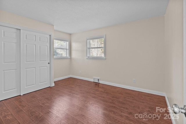 unfurnished bedroom featuring dark hardwood / wood-style flooring and a closet