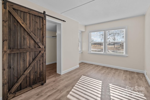 unfurnished bedroom featuring a barn door and light wood-type flooring