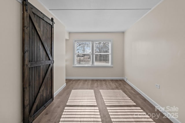 interior space featuring hardwood / wood-style floors, ornamental molding, and a barn door