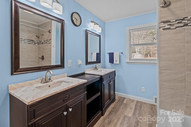 bathroom featuring hardwood / wood-style flooring, tiled shower, vanity, and crown molding