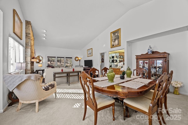 carpeted dining area featuring a wealth of natural light and high vaulted ceiling