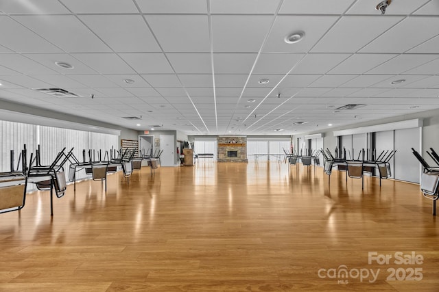 gym with a paneled ceiling and light hardwood / wood-style flooring