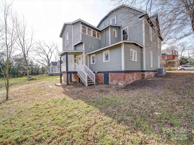 back of property featuring a yard and central AC