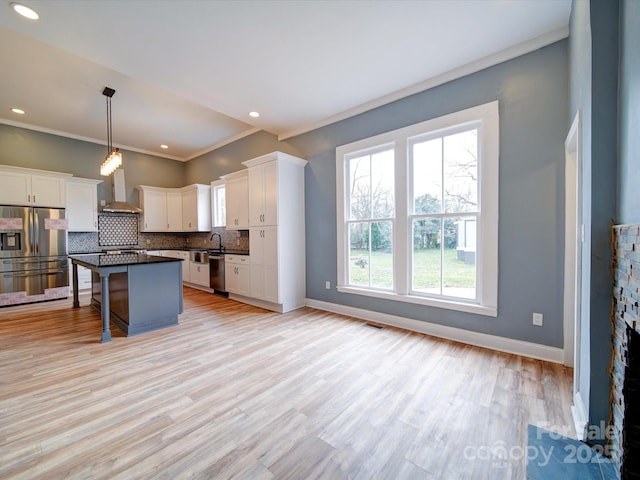 kitchen featuring pendant lighting, a breakfast bar area, appliances with stainless steel finishes, white cabinetry, and a center island