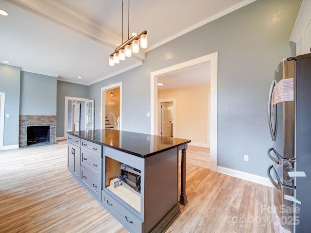 kitchen with hanging light fixtures, crown molding, light hardwood / wood-style flooring, and stainless steel refrigerator