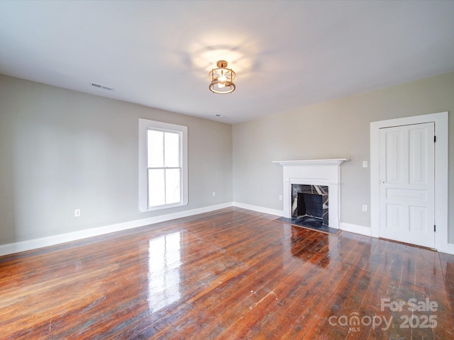 unfurnished living room featuring a premium fireplace and dark hardwood / wood-style floors