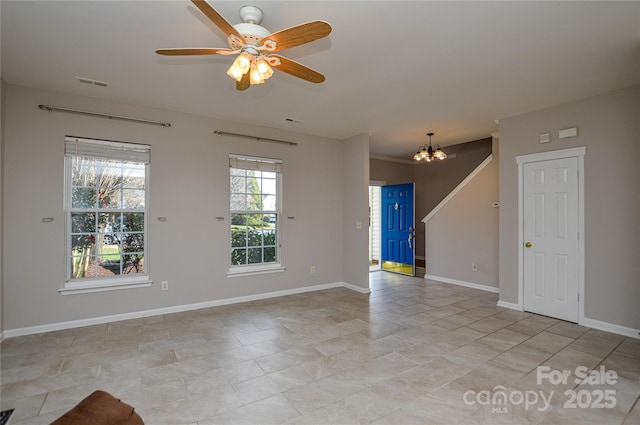 spare room with ceiling fan with notable chandelier, baseboards, and visible vents