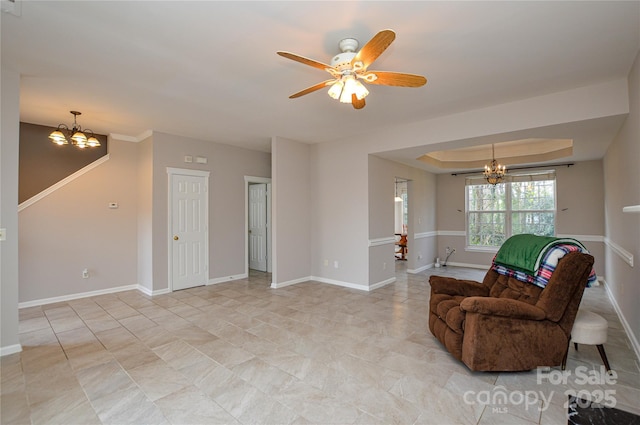 living area with ceiling fan with notable chandelier, a raised ceiling, and baseboards