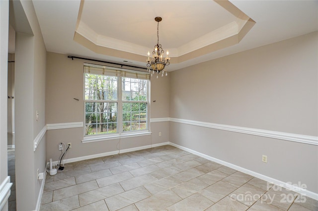 empty room featuring a tray ceiling, baseboards, and a chandelier