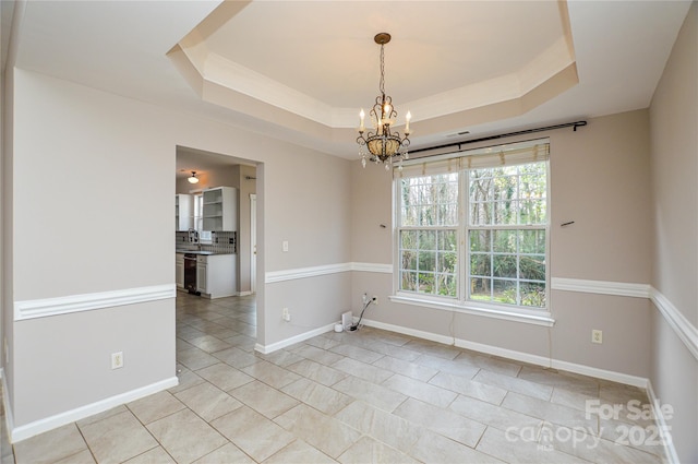 spare room featuring a tray ceiling, wine cooler, baseboards, and a chandelier