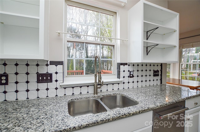 kitchen featuring light stone counters, decorative backsplash, white cabinetry, and a sink