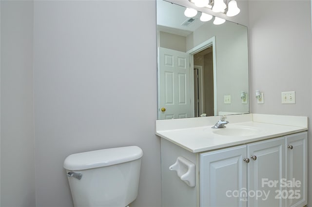 half bath with visible vents, toilet, and vanity