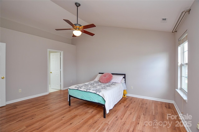 bedroom featuring a ceiling fan, baseboards, light wood finished floors, visible vents, and lofted ceiling