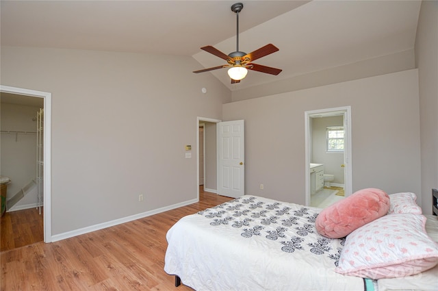 bedroom with a walk in closet, baseboards, light wood-type flooring, lofted ceiling, and a ceiling fan