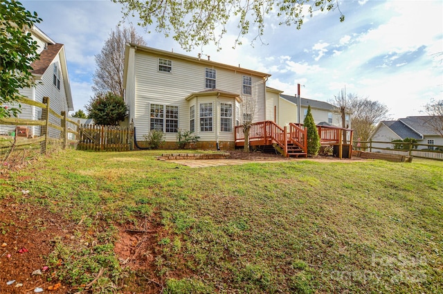 rear view of property with a deck, a lawn, and a fenced backyard