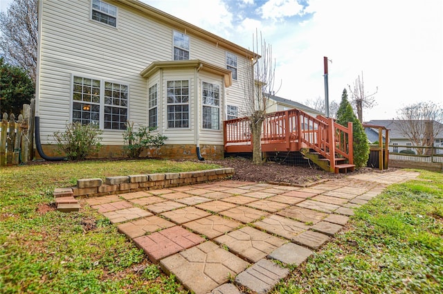 back of house featuring a wooden deck, a patio area, a yard, and fence