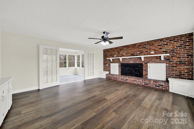 unfurnished living room with dark hardwood / wood-style flooring, a brick fireplace, ceiling fan, and brick wall