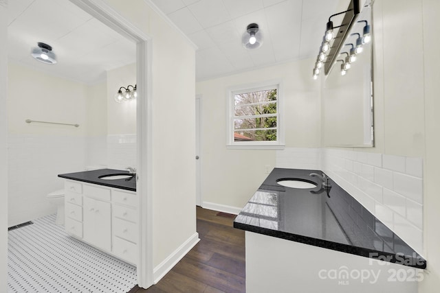 bathroom with wood-type flooring, tile walls, vanity, toilet, and crown molding